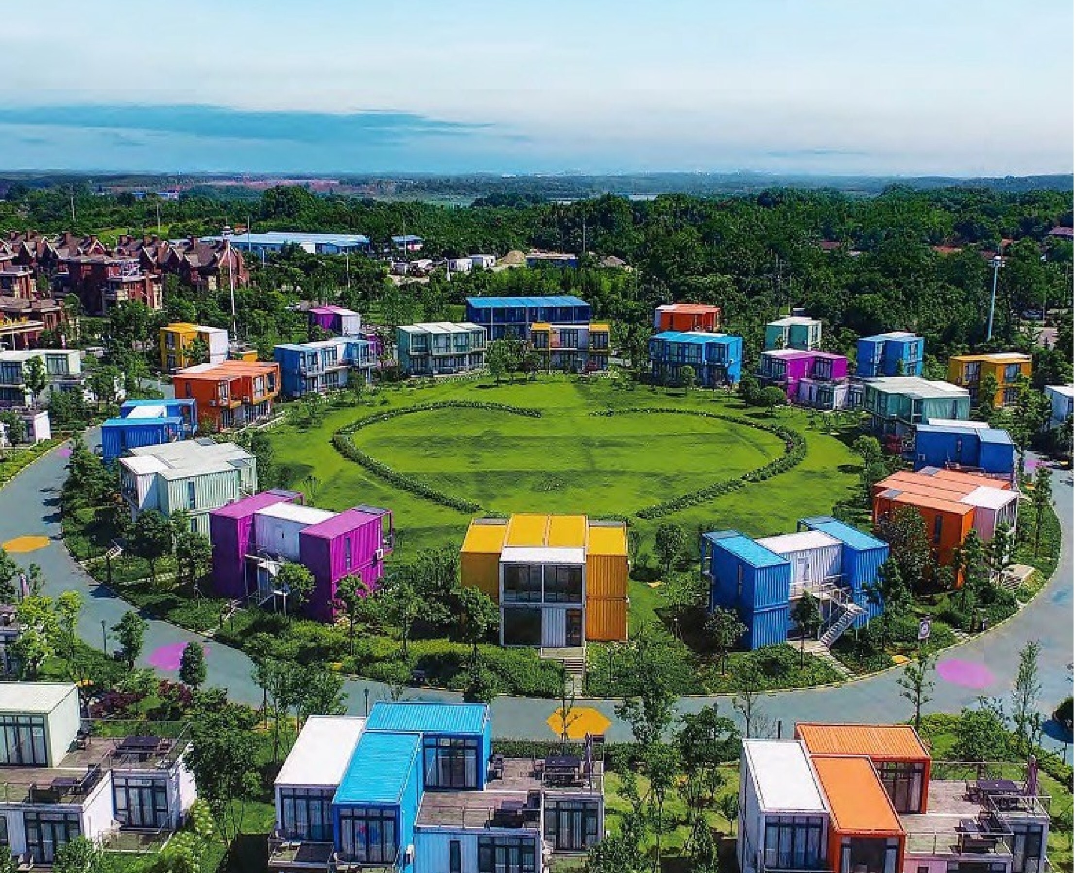 Aerial view of a colourful modular Honeymoon Hotel & Leisure complex arranged around a central green lawn